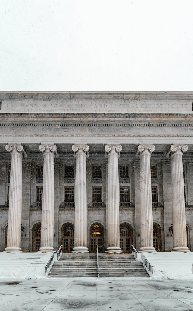 Majestic courthouse facade with columns and stairs blanketed in snow, capturing Denver's winter charm.